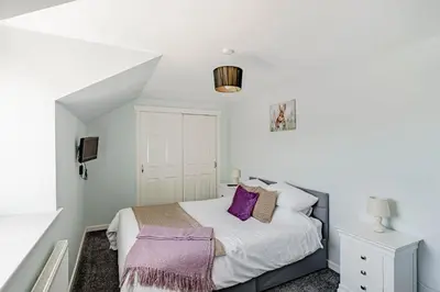 a bedroom with a bed with purple pillows at Auchenlarie Courtyard No 1 in Gatehouse of Fleet