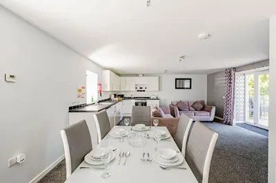 a dining room and kitchen with a white table and chairs at Auchenlarie Courtyard No 1 in Gatehouse of Fleet