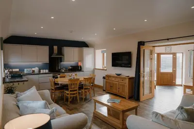 a living room with a kitchen and a dining room at Country cottage with garden, views & games room in Dumfries