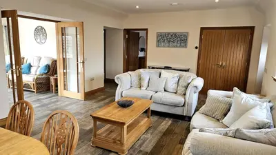 a living room with two couches and a table at Country cottage with garden, views & games room in Dumfries