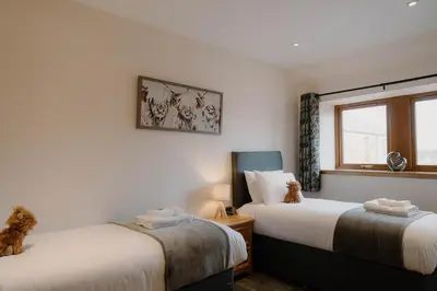 a bedroom with two beds and a window at Country cottage with garden, views & games room in Dumfries