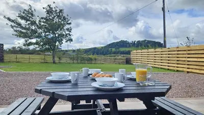 a wooden picnic table with food and drinks on it at Country cottage with garden, views & games room in Dumfries