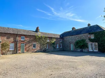 an old brick building with a driveway in front of it at Bank House Longtown, ideal group accommodation with swimming pool & hot tub in Longtown
