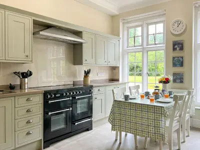 a kitchen with a stove and a table with chairs at Bank House Longtown, ideal group accommodation with swimming pool & hot tub in Longtown