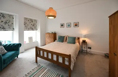 a bedroom with a bed and a blue couch at Ayrbados - 4 bed townhouse in Ayr in Ayr