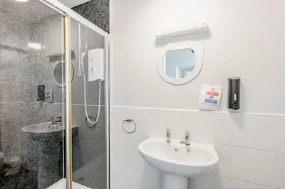 a white bathroom with a sink and a shower at Auchenlarie Courtyard No 3 in Gatehouse of Fleet