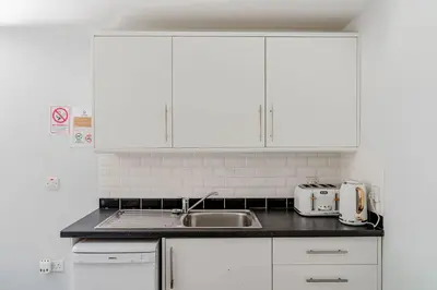 a kitchen with white cabinets and a sink at Auchenlarie Courtyard No 3 in Gatehouse of Fleet