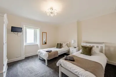 a bedroom with two beds and a tv and a window at Auchenlarie Farmhouse in Gatehouse of Fleet