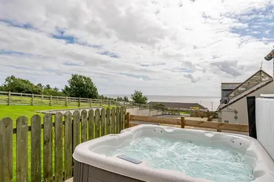 a bath tub on a patio with a fence at Auchenlarie Courtyard No 5 in Gatehouse of Fleet