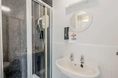 a white bathroom with a sink and a mirror at Auchenlarie Courtyard No 5 in Gatehouse of Fleet