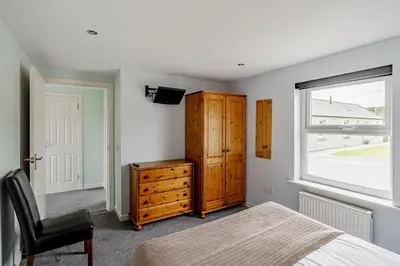a bedroom with a bed and a dresser and a window at Auchenlarie Courtyard No 5 in Gatehouse of Fleet