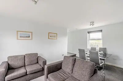 a living room with a couch and a table and chairs at Auchenlarie Courtyard No 5 in Gatehouse of Fleet