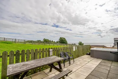 a wooden deck with a bench and a bath tub at Auchenlarie Courtyard No 5 in Gatehouse of Fleet