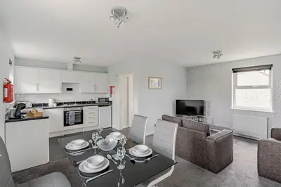 a kitchen and a living room with a table and chairs at Auchenlarie Courtyard No 5 in Gatehouse of Fleet