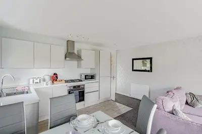 a kitchen and a living room with a pink couch at Auchenlarie Courtyard No 4 in Gatehouse of Fleet