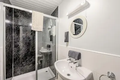 a white bathroom with a sink and a shower at Auchenlarie Courtyard No 2 in Gatehouse of Fleet
