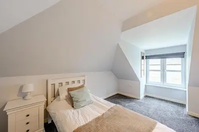 a bedroom with a bed and a dresser and a window at Auchenlarie Courtyard No 2 in Gatehouse of Fleet
