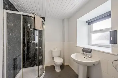 a bathroom with a shower and a toilet and a sink at Auchenlarie Courtyard No 2 in Gatehouse of Fleet