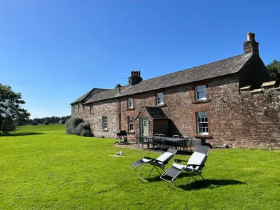 two chairs and a table in front of a brick building at Kirk House Longtown, ideal for groups or families holidaying together in Longtown