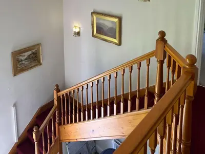 a wooden staircase with two pictures on the wall at Kirk House Longtown, ideal for groups or families holidaying together in Longtown