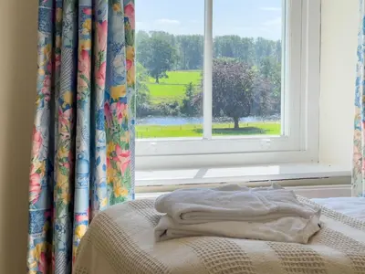 a bed in a room with a window and a blanket at Kirk House Longtown, ideal for groups or families holidaying together in Longtown