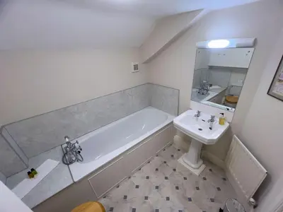 a white bathroom with a tub and a sink at Kirk House Longtown, ideal for groups or families holidaying together in Longtown