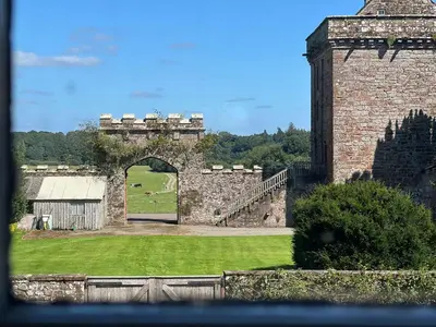 an old brick building with an archway in a field at Kirk House Longtown, ideal for groups or families holidaying together in Longtown