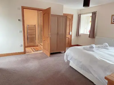 a bedroom with a bed and a closet and a window at Dungavel Cottage in Roberton