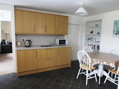 a kitchen with wooden cabinets and a table with chairs at Swallow Cottage in Dalbeattie
