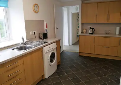 a kitchen with a washing machine and a sink at Swallow Cottage in Dalbeattie