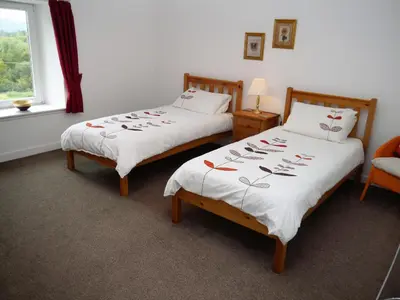 two twin beds in a room with a window at Swallow Cottage in Dalbeattie