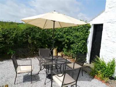 a table and chairs with an umbrella on a patio at Swallow Cottage in Dalbeattie
