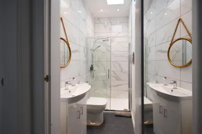 a bathroom with two sinks and a shower and a toilet at Hunter Links Cottage in Prestwick