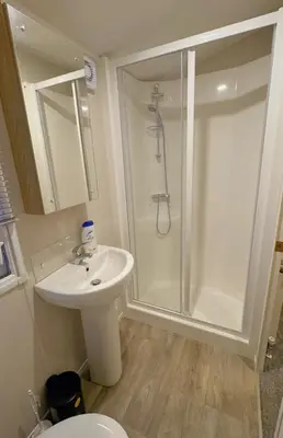 a white bathroom with a shower and a sink at Carlisle CAMELOT HOLIDAY PARK CA65SZ MANOR in Longtown