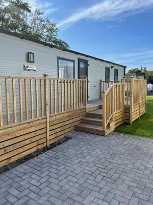 a house with a wooden fence and a patio at Carlisle CAMELOT HOLIDAY PARK CA65SZ MANOR in Longtown