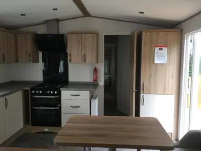 a kitchen with wooden cabinets and a wooden table at Carlisle CAMELOT HOLIDAY PARK CA65SZ Blenheim in Longtown