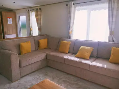 a living room with a brown couch with yellow pillows at Carlisle CAMELOT HOLIDAY PARK CA65SZ Blenheim in Longtown