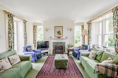 a living room with green couches and a fireplace at Bellrigg in Castle Douglas