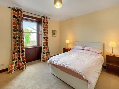 a bedroom with a large bed and a window at Arden in Glenluce
