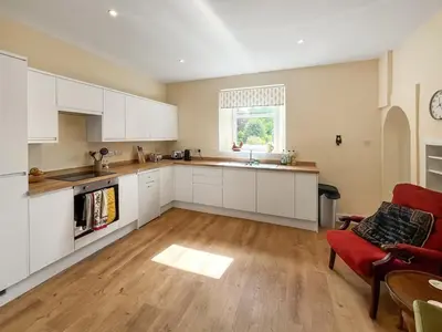 an open kitchen with white cabinets and a red couch at Arden in Glenluce
