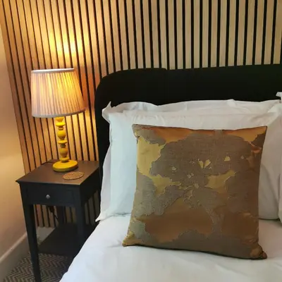 a bed with a pillow and a table with a lamp at The Swinside Inn in Keswick