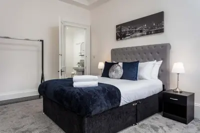 a bedroom with a large bed with a blue blanket at St Meddans Mews in Troon in Troon