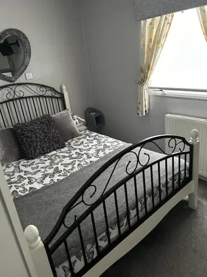 a bedroom with a bed with a black and white comforter at Cairnryan Heights home from home in Cairnryan