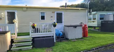 a tiny house with a porch and a fence at Cairnryan Heights home from home in Cairnryan