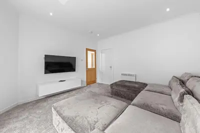 a living room with a couch and a flat screen tv at The Manor - Beachwalk Apartments in Ayr