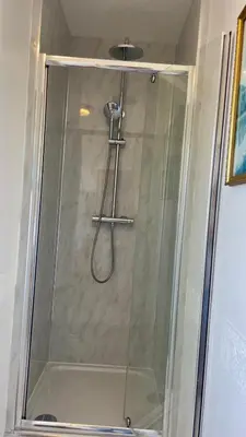 a shower with a glass door in a bathroom at Room with Newly Renovated Private Bathroom above Village Pub Stag Inn Crosby Maryport in Maryport