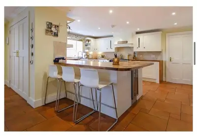 a kitchen with white cabinets and a counter with bar stools at Brig o Doon House Alloway in Ayr