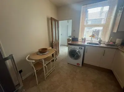 a kitchen with a washing machine and a table at Lonsdale Terrace - 3 Bedrooms - Sleeps 6 in Workington