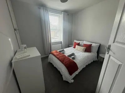 a bedroom with a bed with red pillows and a window at Lonsdale Terrace - 3 Bedrooms - Sleeps 6 in Workington