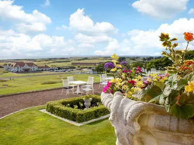 a garden with tables and chairs and flowers on a hill at Royal Aberdeen - Ukc6917 in Turnberry